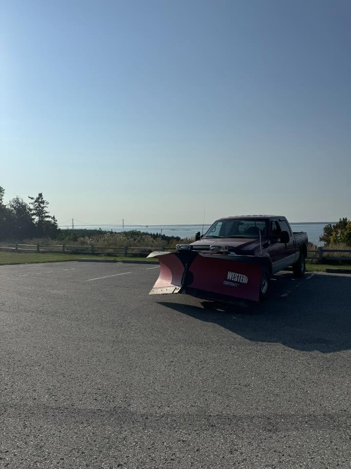 Snowplow truck in an open parking lot overlooking a lake